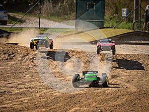 Three offroad RC cars racing on a track