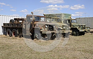 Three old army vehicles parked in a grass field
