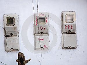 three old electrical meters installed on a white wall