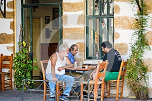 Three old men sitting at greek taverna and playing backgammon