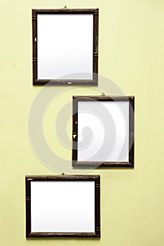 Three old rustic blank frames on a light yellow wall