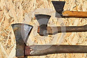 Three old rusty axe tools on plywood background.