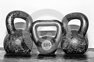 Three old and rusty KettleBells on the gym floor photo