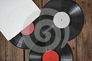 Three old vinyl records in paper case on wooden rustic background.