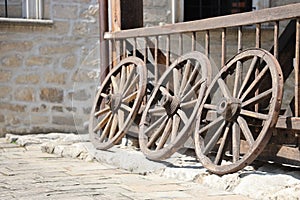 Three old wooden wheels for horse carts leaning against a wooden wall