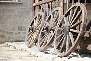 Three old wooden wheels for horse carts leaning against a wooden wall