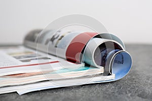 Three open magazines on grey stone table