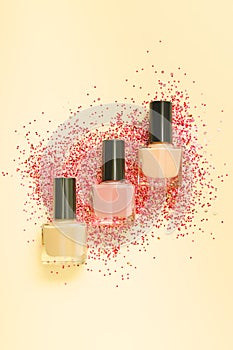 Three orange nail polish bottles on yellow background. Set of yellow nail polish bottles with glitter red decoration