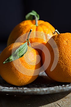 Three oranges lying on an old metal cake stand