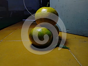 three oranges are stacked on the yellow floor dark background and blur
