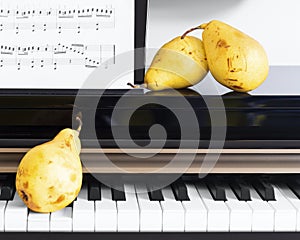 Three organic yellow pears placed on the piano key
