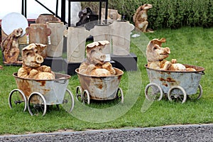 Three ornamental pottery pigs in bathtubs on wheels, at a craft