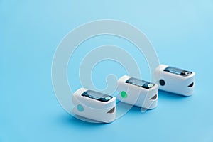 Three oximeters on a blue background. Medical devices for measuring blood oxygen saturation. Top view