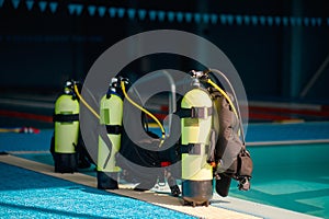 Three oxygen tanks at poolside, diving equipment