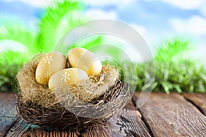 Three painted Easter eggs in the nest on table and nature background