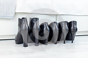 three pairs of black boots with high heels in front of a white closet