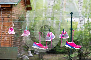 Three pairs of bright sport fitness sneakers hanged on clothespin at backyard after laundry outdoors. Preparartion for running