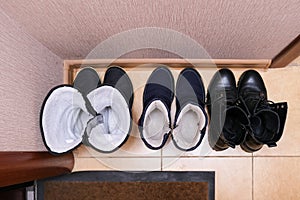 Three pairs of casual winter shoes on the floor at the home entrance, family footwear in the corridor, hall