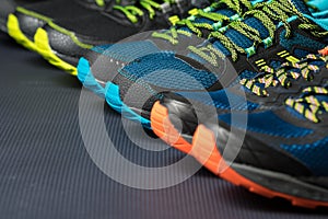 Three pairs of colorful running trainers / exercise shoes on the floor of a sport / shoe shop