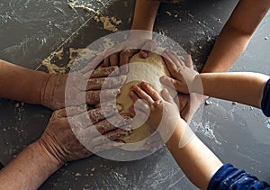 Three pairs of hands holding the dough