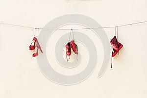 Three pairs of red shoes tied to a thread.
