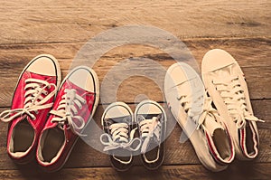 Three pairs of shoes lay on the wooden floor of the family, parents and children to do together