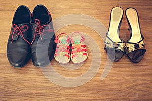 Three pairs of shoes: men, women and children.