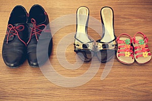 Three pairs of shoes: men, women and children. Baby sandals stand next to womens shoes.