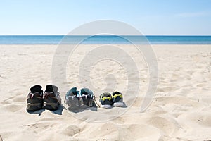 Three pairs of sneakers are on the sand. The concept of the weekend