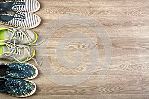 Three pairs of various running shoes laid on a wooden floor background.