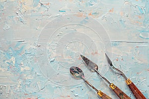 Three palette knifes on artist canvas with oil paint