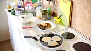 Three pancakes are fried in a frying pan, on an electric stove, against the background of the kitchen table.