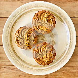 Three Pandan MoonCake in a plate on wooden background. Aerial view.