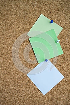 Three paper notes green, white and yellow color on a cork Board, attached with a white pushpin. Copy space