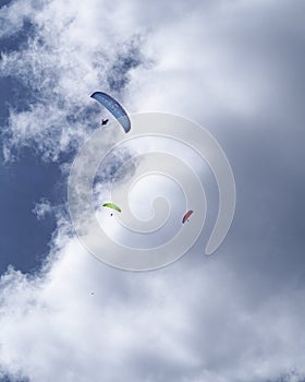 Three parachutes flying over the blue sky with clouds.