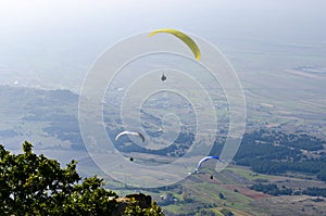 Three paraglider flies paraglider over the tops of the mountains