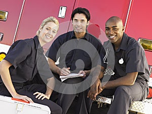 Three paramedics chatting by ambulance