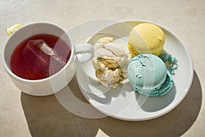 Three Parisian-style macarons and cup with cardamon tea