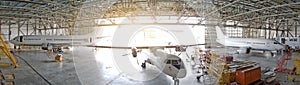 Three passenger aircraft in a hangar with an open gate for service, view of the panorama.