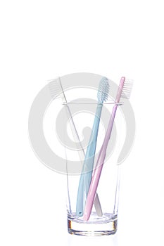 Three pastel shades Toothbrushes in glass isolated on white background