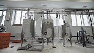 Three pasteurization tanks with ladder at factory. Worker passes through it