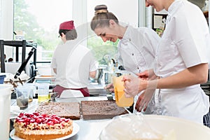 Three pastry bakers in confectionary preparing fruit pies photo