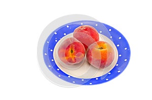 Three peach in blue plate isolated on white