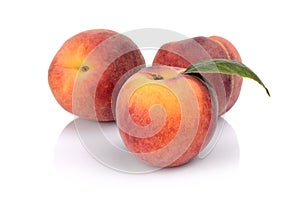 Three peaches with leaf isolated on white