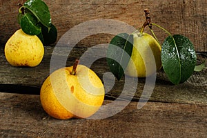 Three pears with leaves on a wooden surface