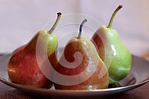 Three pears, pears lying on the plate, red-green pears