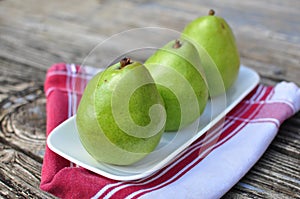 Three Pears on the white plate wooden background