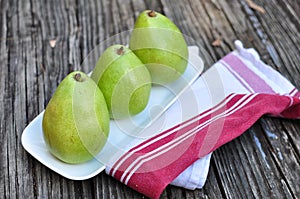 Three Pears on the white plate wooden background