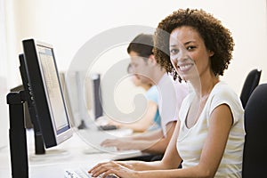 Three people in computer room typing and smiling