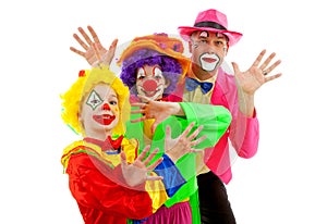 Three people dressed up as colorful funny clowns